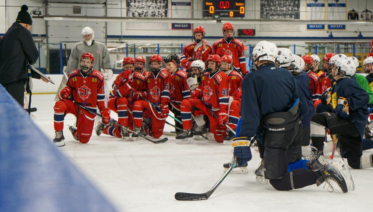 HUDDLE UP. The Järfälla and Spartan teams watch as Spartan hockey coach Bill McClellan draws out a drill on his whiteboard.