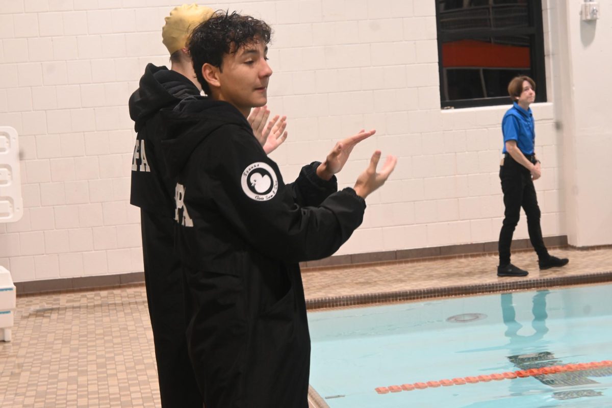 YOUTH SUPPORT. Junior Sam Galarneault show his support to the younger middle schoolers on the Trojan Swim and Dive team. 