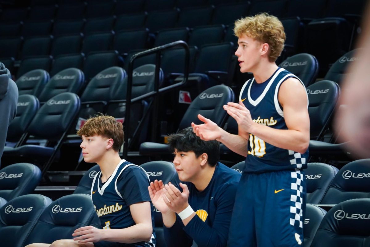 CHEER. Sophomore Palmer Olson stands up to cheer his teammates on.