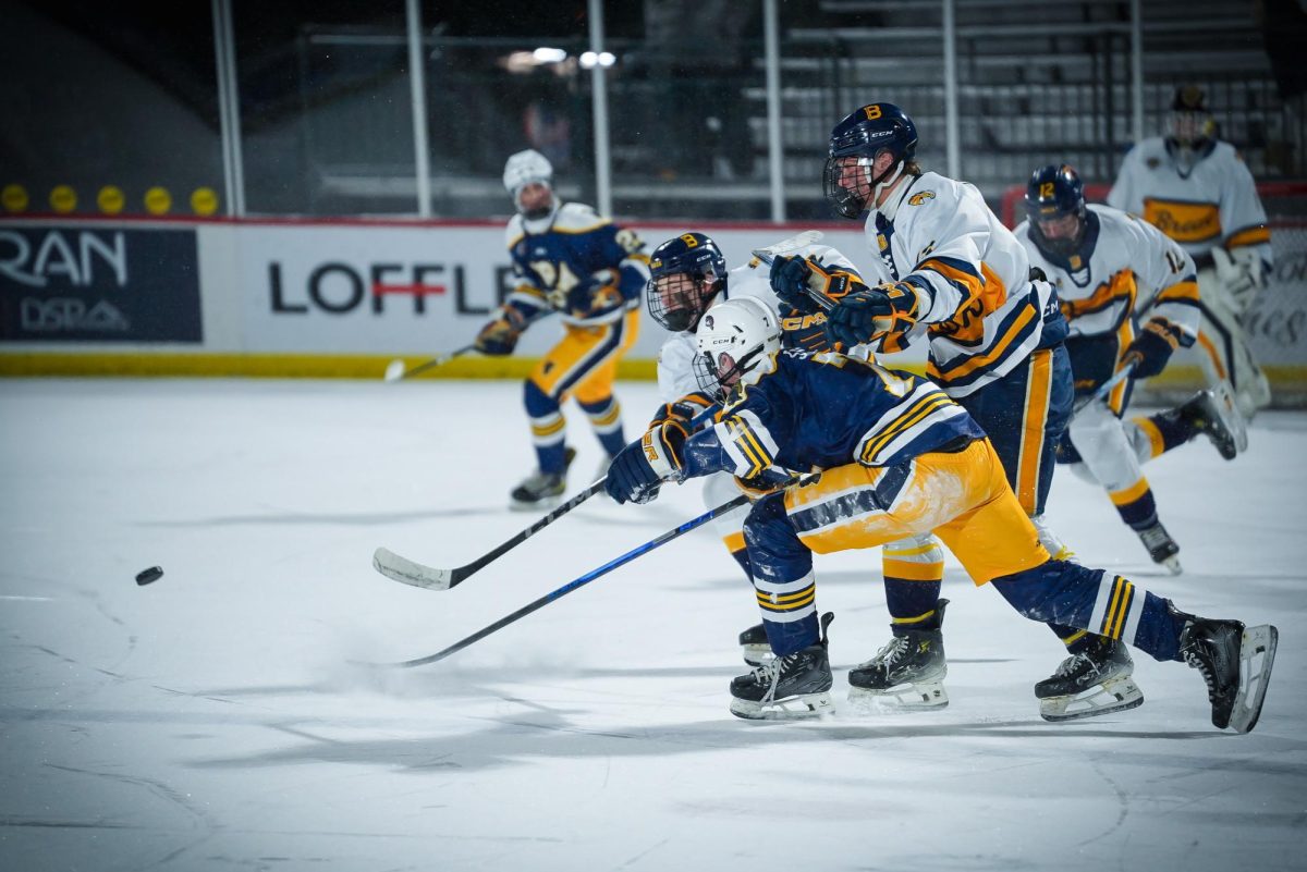 SKATE. A Spartan and a Mustang player go after the puck.