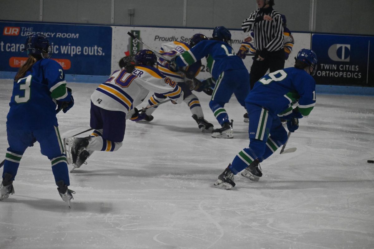 SCRAMBLE FOR THE PUCK. Players from both teams skate towards the puck trying to regain possesion