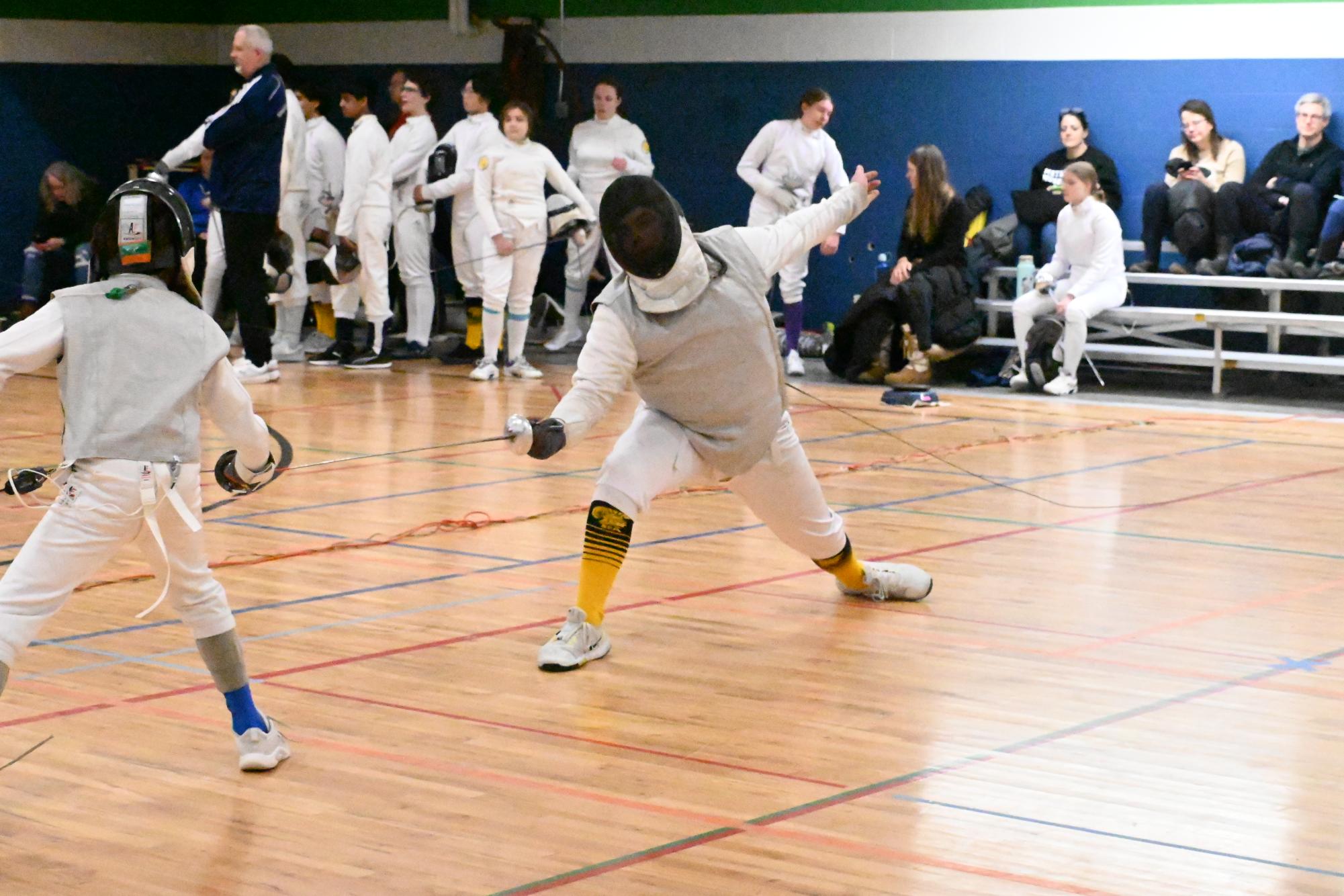 Junior Griffin Roy leaps in an attack against an opponent in a fencing match. 