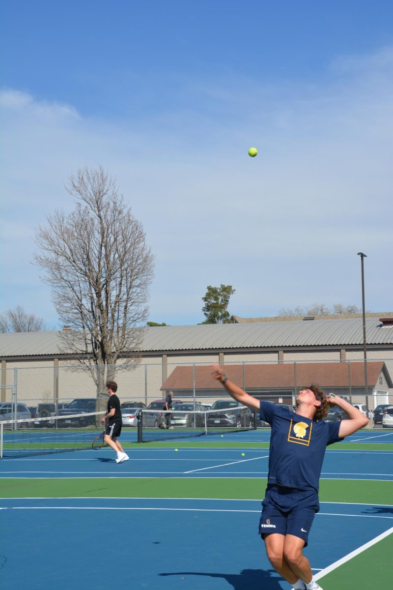 BASELINE FOCUS. Senior Elliot Sjaastad poises to strike a powerful serve during a set against Edina. Relying on height and timing, Sjaastad uses his service game to put immediate pressure on his opponent and dictate the opening of the point.