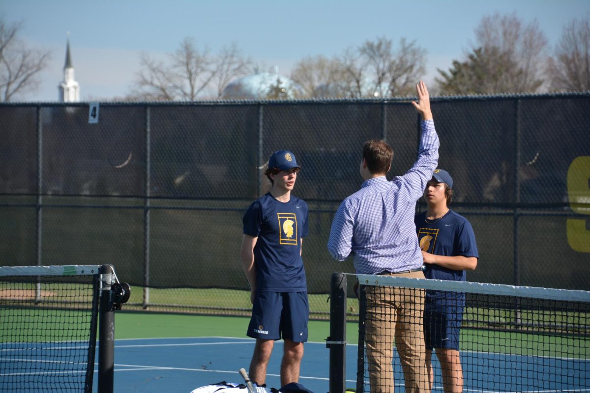 COURTSIDE COUNSEL. No. 1 doubles partners Henry Cammack and Isaak Senaratna listen as coach Luke Elifson provides tactical adjustments between games. The mid-match huddle allowed the duo to recalibrate their strategy as they prepared to reclaim the momentum in the following game.