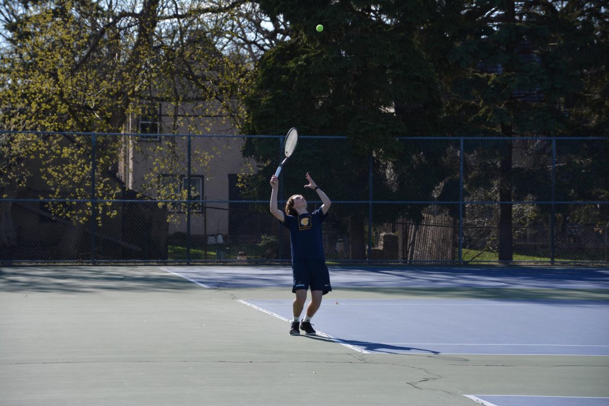 EYE ON THE BALL. Sophomore Nolan Rosenberger tracks his toss as he prepares to deliver a serve against Edina. By focusing on a high, consistent release, Rosenberger aims to dictate the pace of the rally and keep his opponent off-balance from the start of the point.