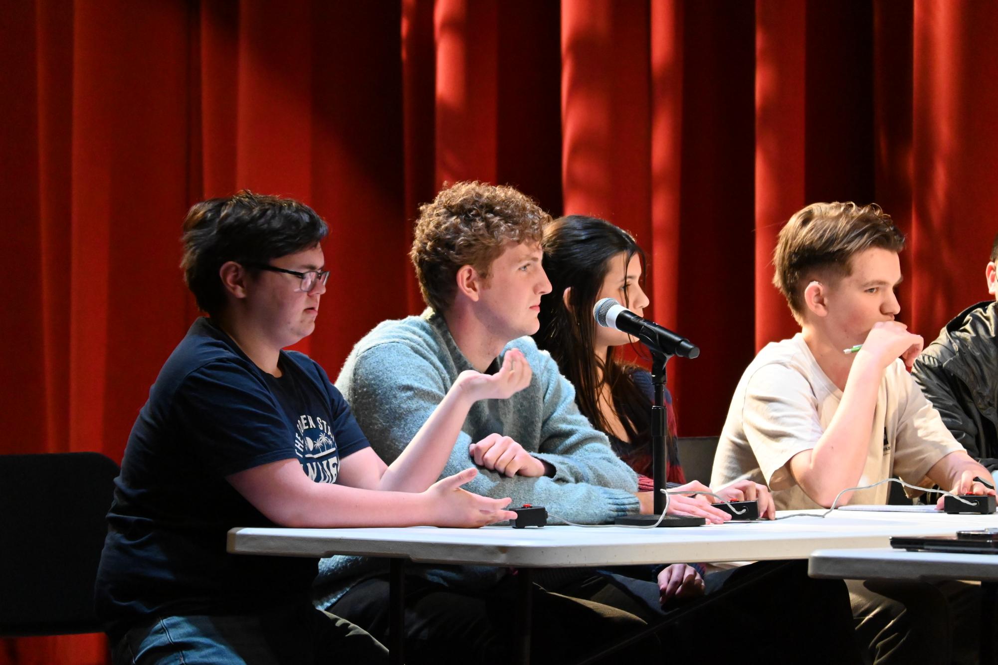 THOUGHTFUL TEAM.  Quiz Bowl teammates take turns answering questions. The Apr. 8 assembly featured six student members and six faculty from various disciplines. Junior Asha Peckosh said that “[It was] close, and that was great, because they’re all experts in their fields.”