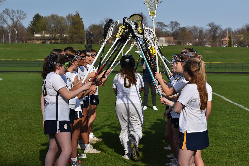 STICKS UP, SUPPORT UP. Before a game, girls lacrosse forms two lines and cheers while starters run through. The lacrosse community can be described simply: tight-knit.